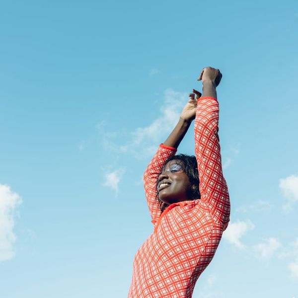 Smiling person stretching outdoors with the sun rising in the background.